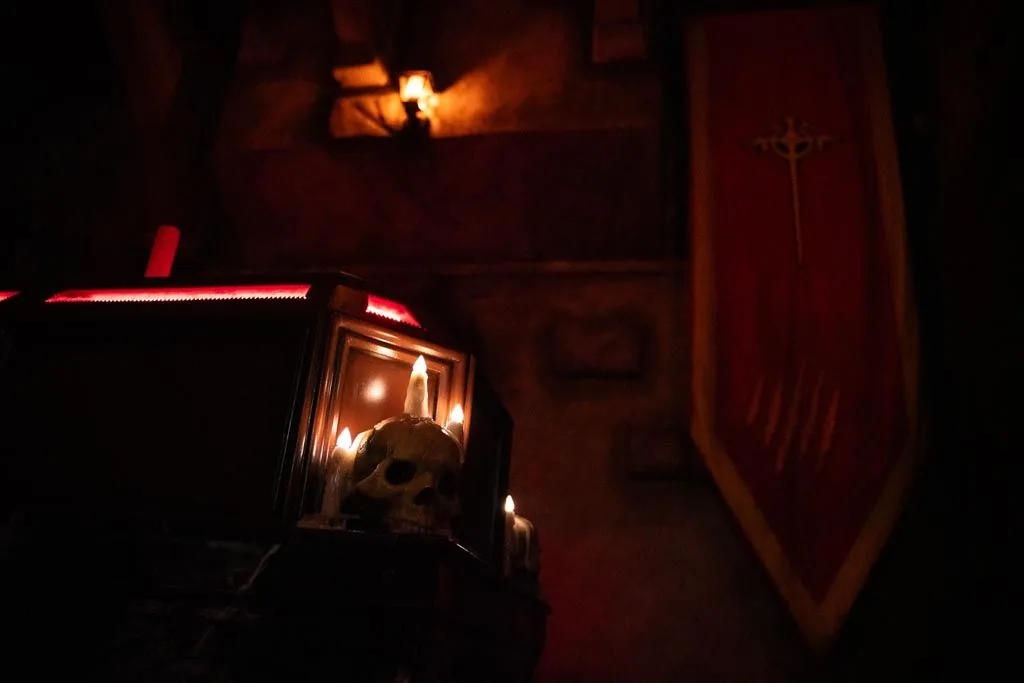 A skull lit red on top of a tomb in Dracula’s crypt